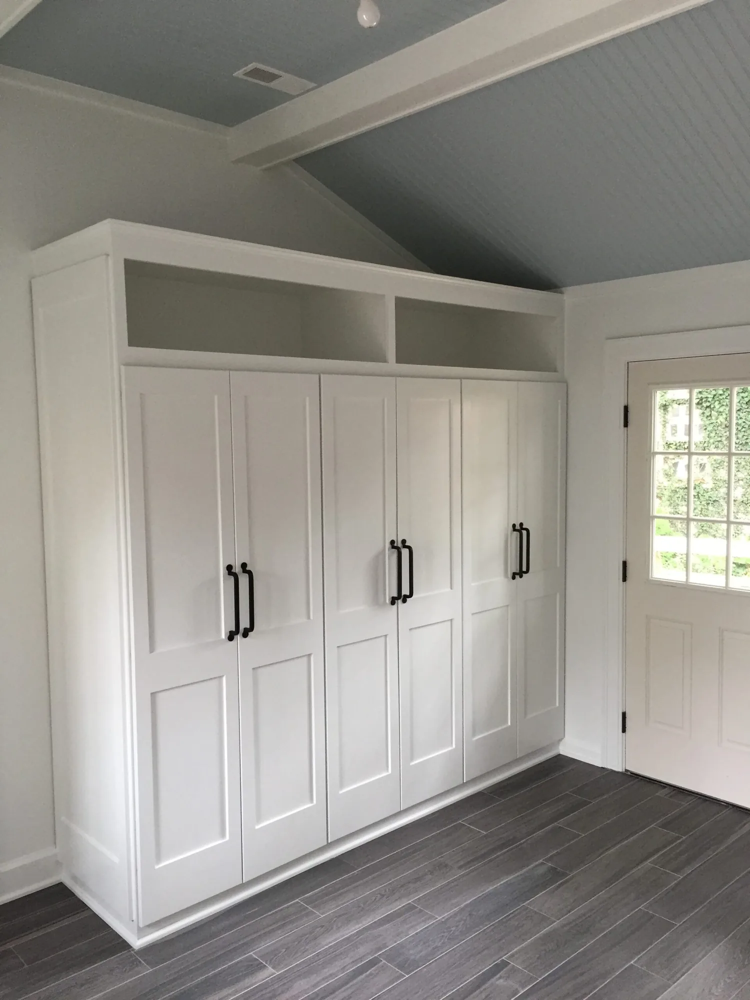 White built-in cabinetry fitted under a sloped ceiling in a bright entry room